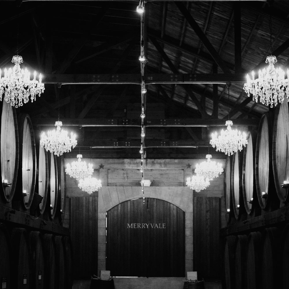 Groom dips bride for a kiss in a chandelier-lit winery barrel room