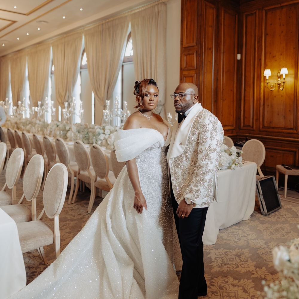 Bride in a sparkling gown and groom in a sequinned jacket in an oak-panelled ballroom