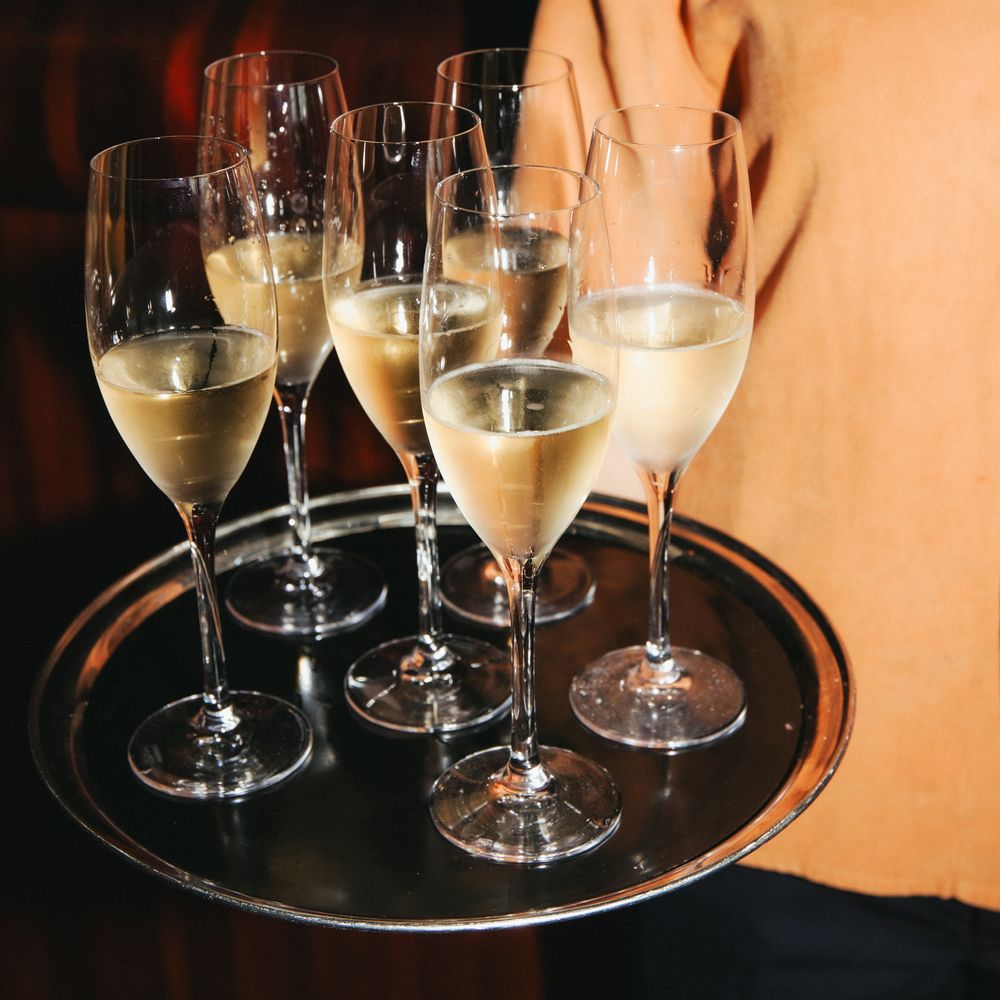 Waiter carrying a silver tray of chilled champagne flutes at a reception