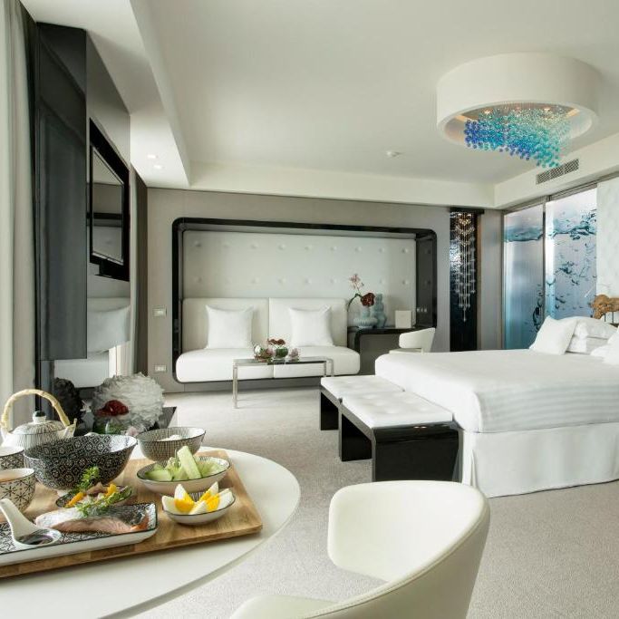 Contemporary luxury hotel suite with white bed, tufted headboard and blue glass chandelier