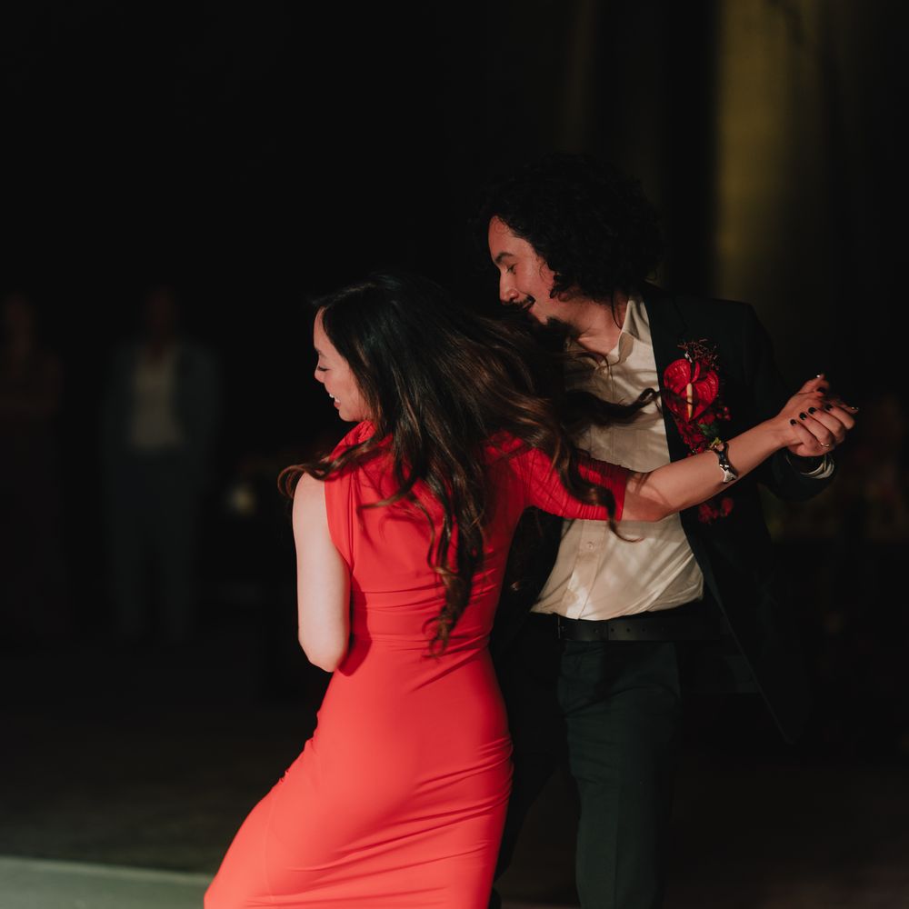 Couple dancing on the floor, woman in red gown and man in dark suit with red buttonhole