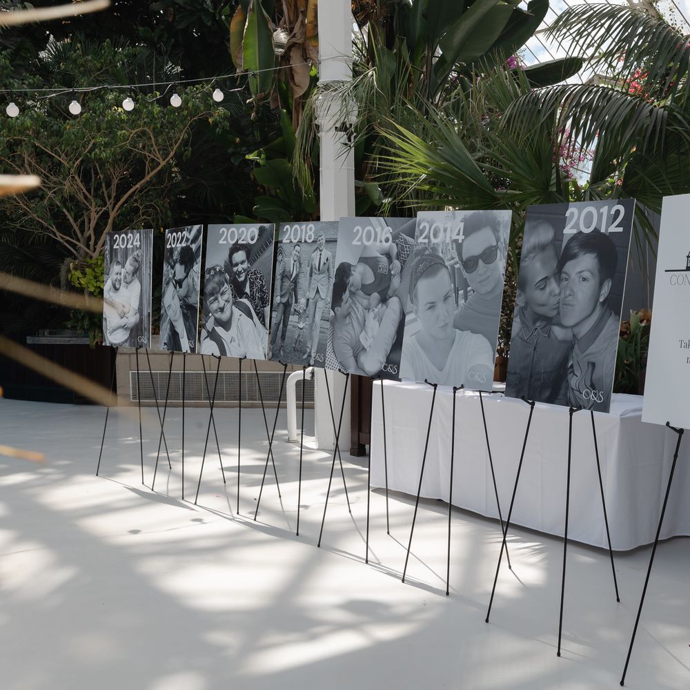 Row of black and white couple photographs on easels dated by year beside a memory lane sign