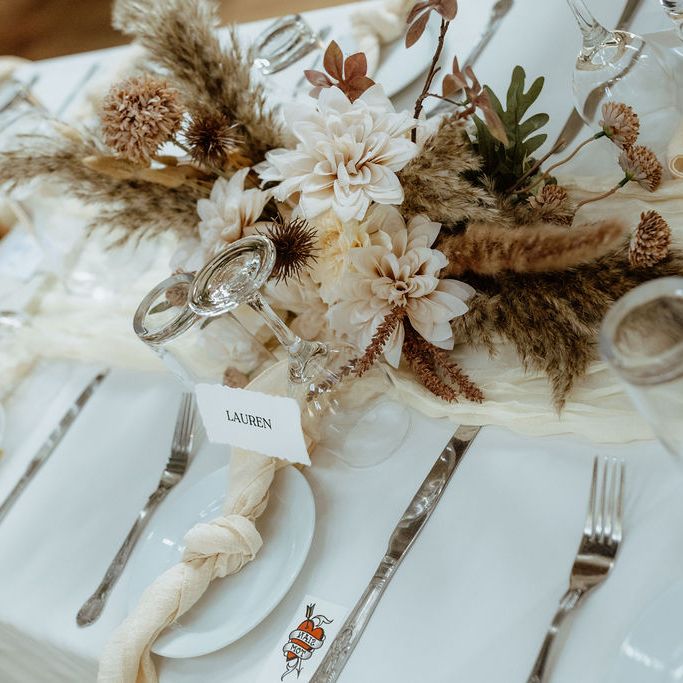 Neutral tablescape with dried florals, knotted napkins and place cards reading Lauren and Simon