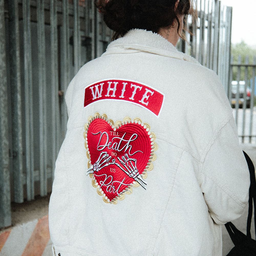 Bride in a cream corduroy jacket with a red heart 'Till Death Do Us Part' embroidered patch