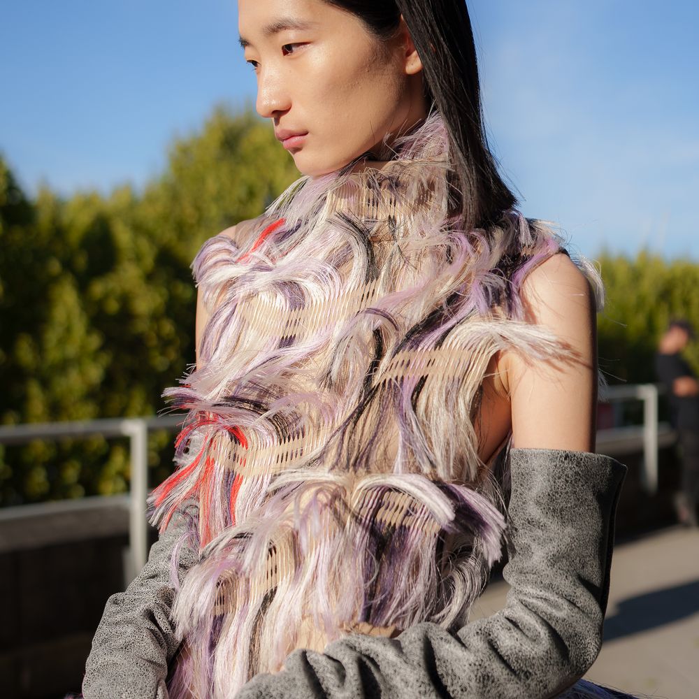 Model in fringed lilac and coral textured gown with grey suede opera gloves outdoors