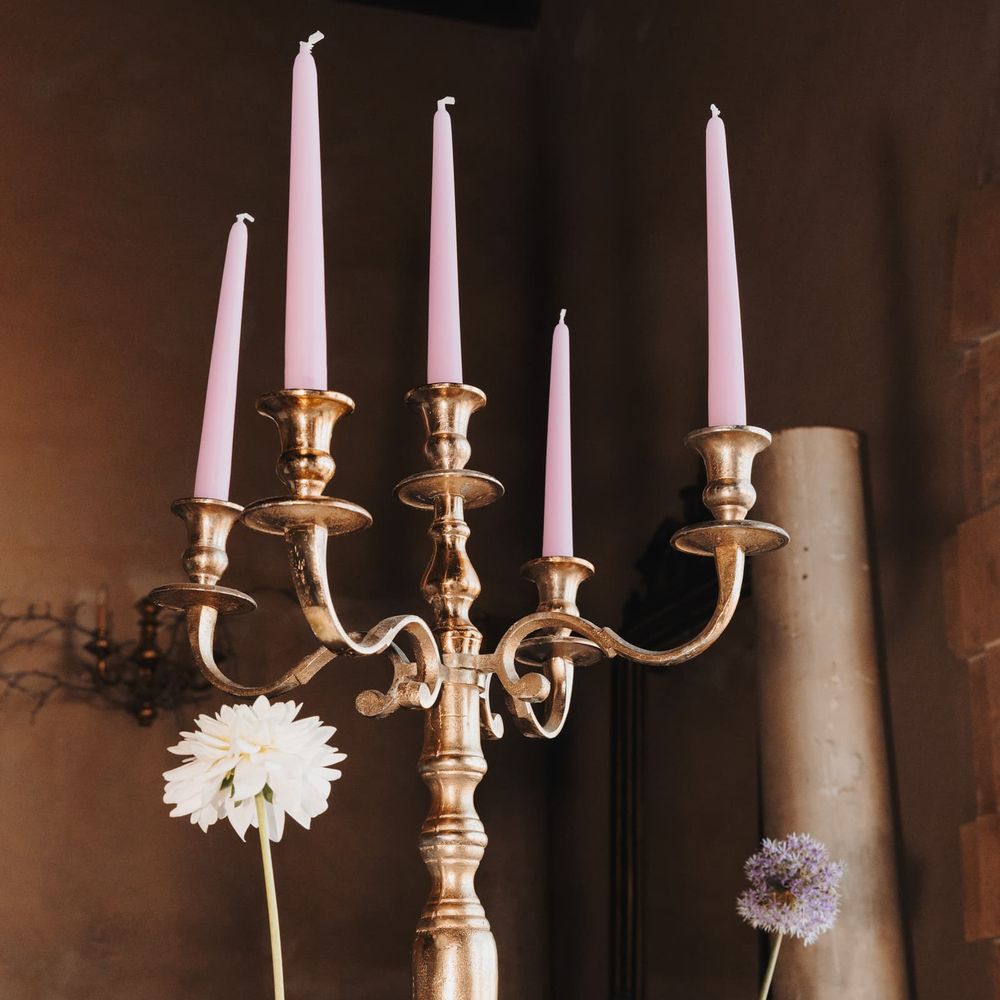 Gold candelabra with pink taper candles above a pastel floral arrangement
