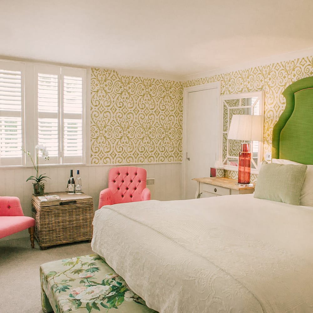 Bridal suite with green upholstered headboard, pink tufted armchairs and patterned wallpaper