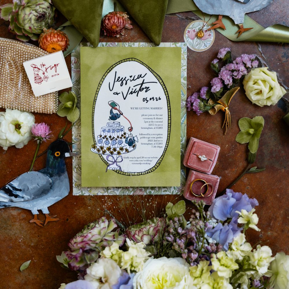 Flatlay of green suede shoes, illustrated invitation, engagement rings and pastel bridal bouquet