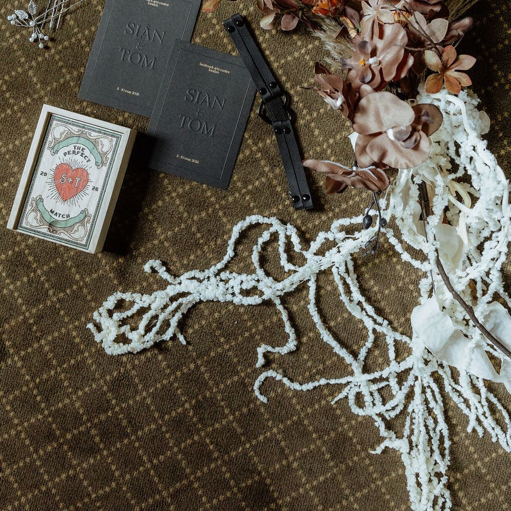 Wedding flat lay with grey stationery, pearl choker, dried florals and matchbox favour