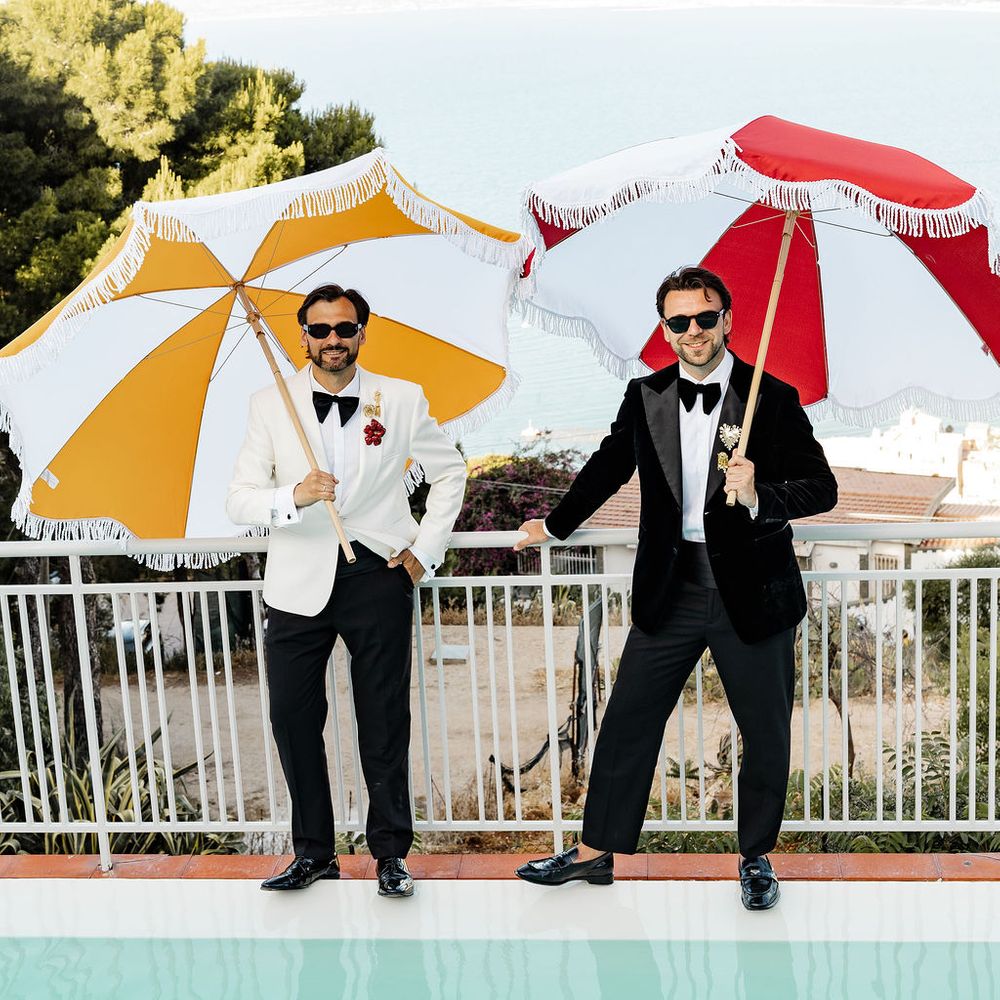 grooms holding fringed umbrellas with seaview