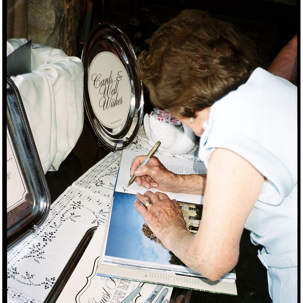 Guest in pale blue writing a message at a cards and well wishes signing table