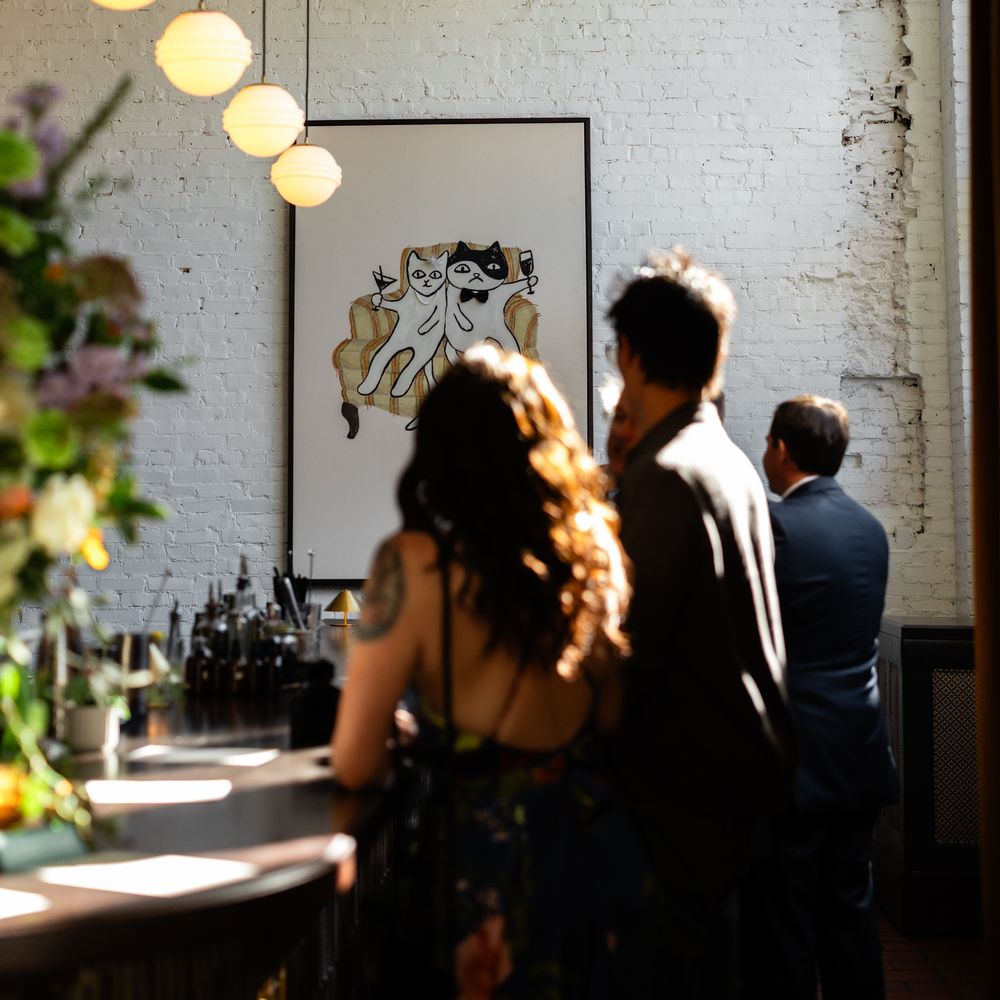 Guests gathered at a bar beneath globe pendant lights with exposed white brick walls