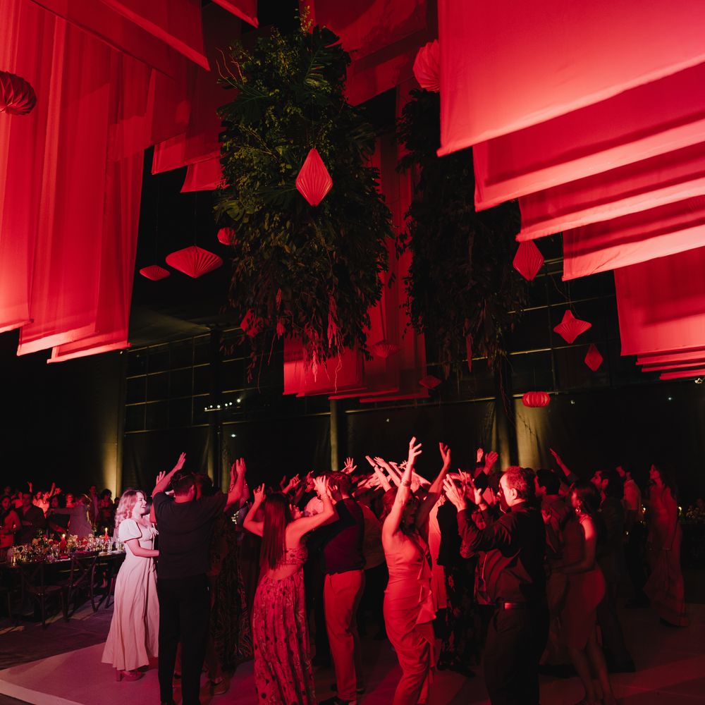 Guests dancing under red draped fabric and hanging foliage at an evening wedding reception