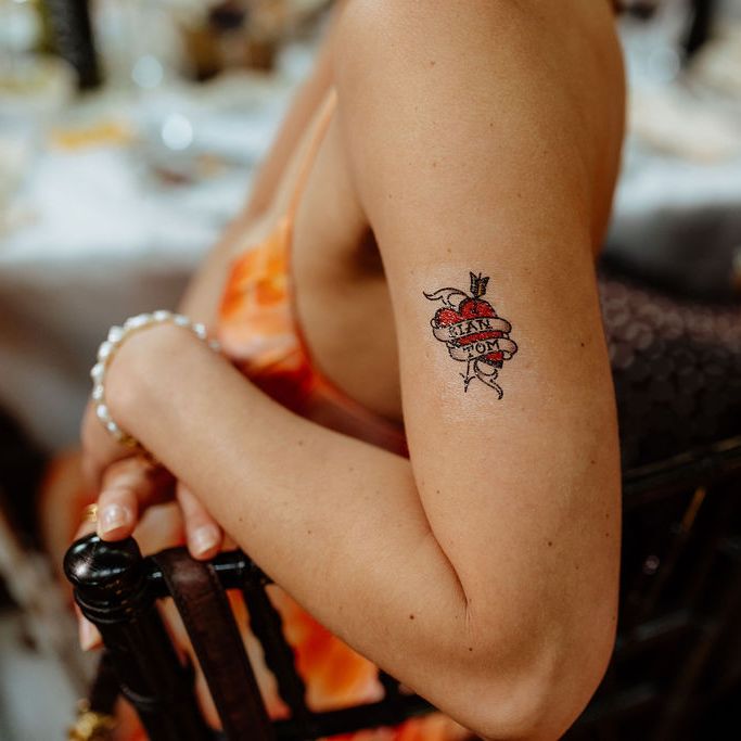 Guest's arm with a heart and banner temporary tattoo at a wedding reception