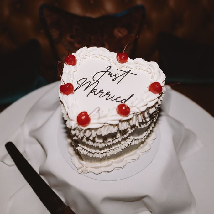 Heart-shaped white wedding cake with cherries and 'Just Married' piped in script
