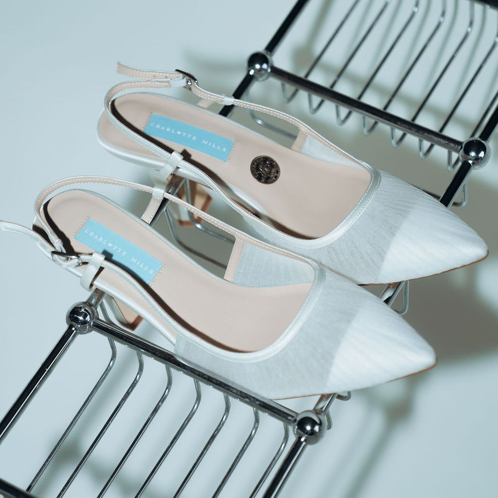 Ivory pointed-toe slingback bridal heels displayed on a chrome wire rack