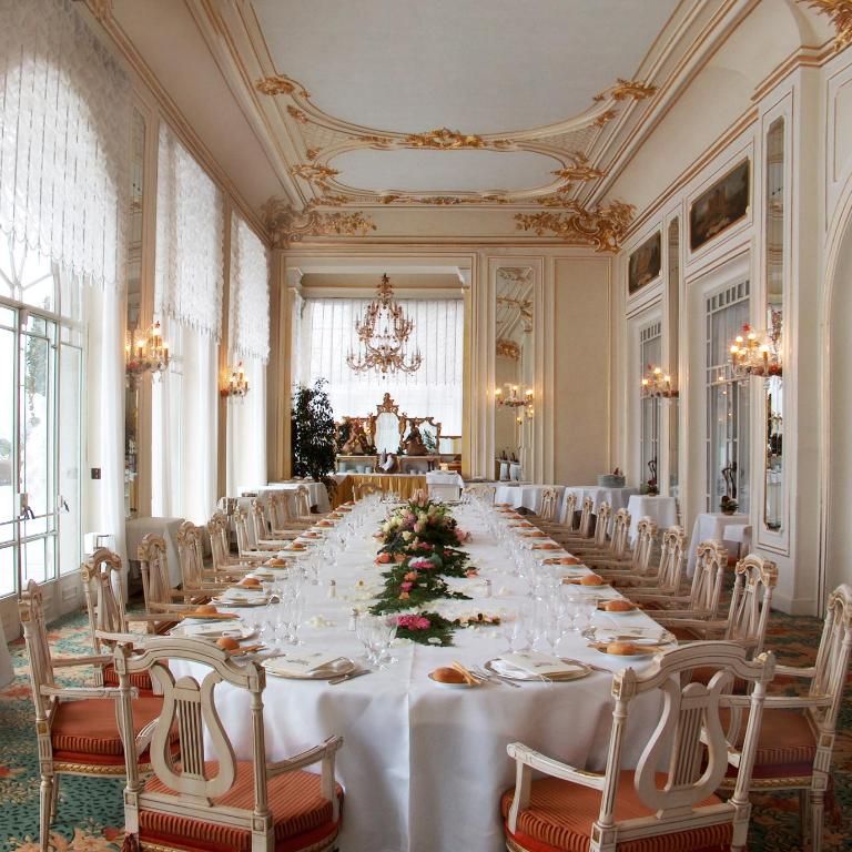 Long banquet table set for a formal wedding breakfast in an ornate gilded ballroom with chandelier