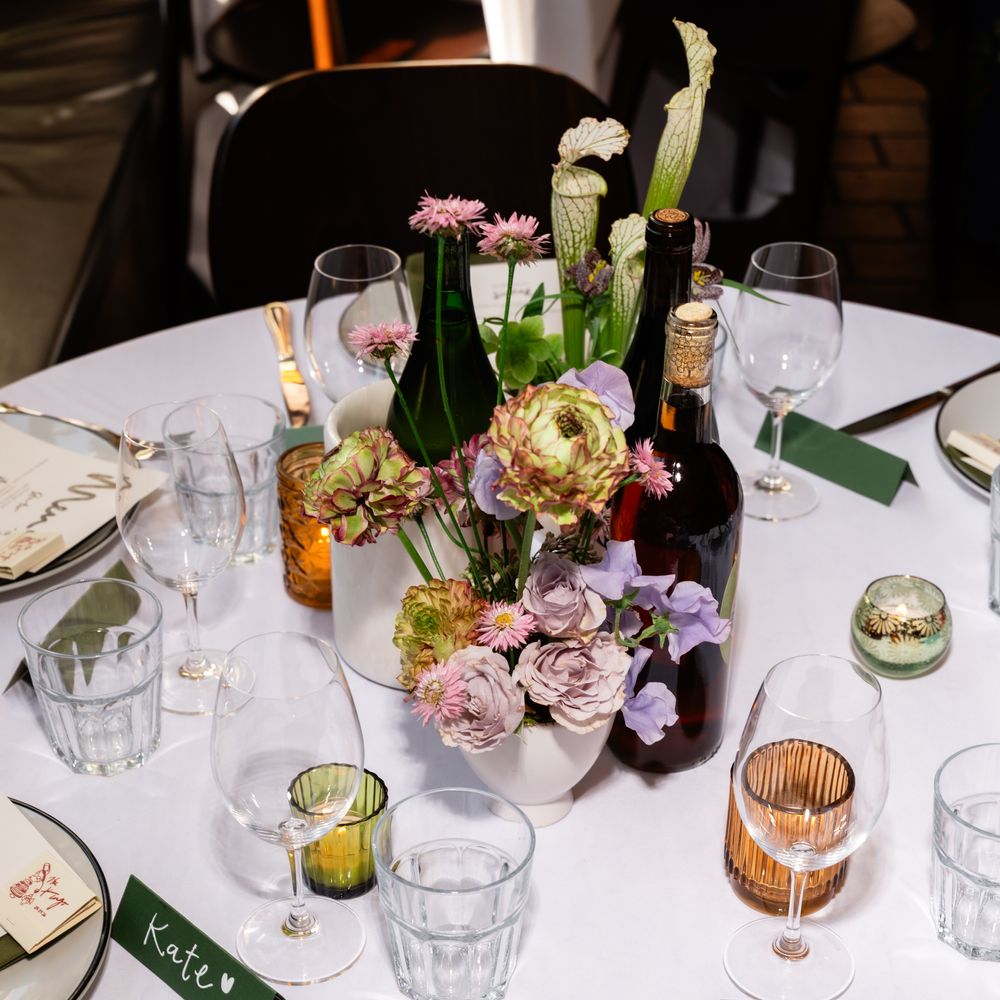 Round wedding table with muted floral centrepiece, handwritten menu and green place cards