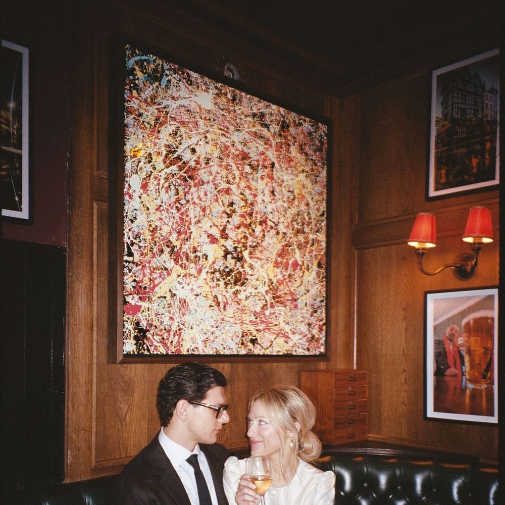Newly married couple share a drink on a leather banquette in a wood-panelled pub