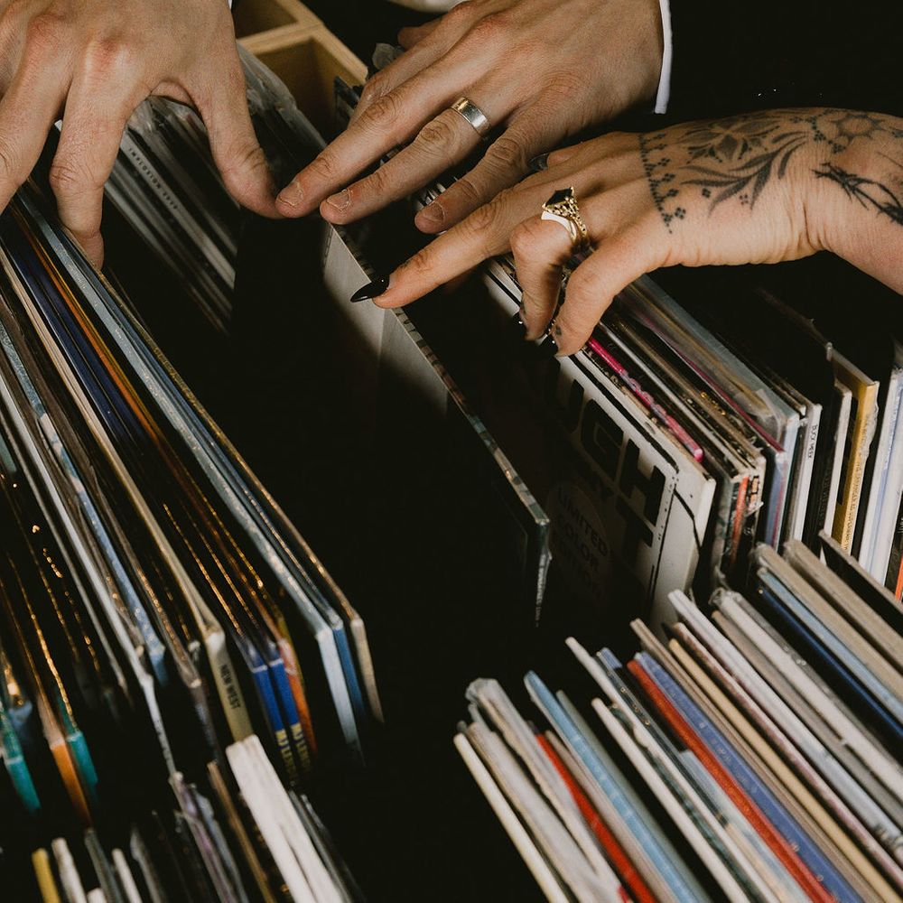 Newlyweds' hands with wedding rings flicking through crates of vinyl records
