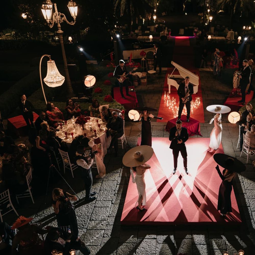 Live band and performers on a lit outdoor stage as guests dine at candlelit tables under lanterns