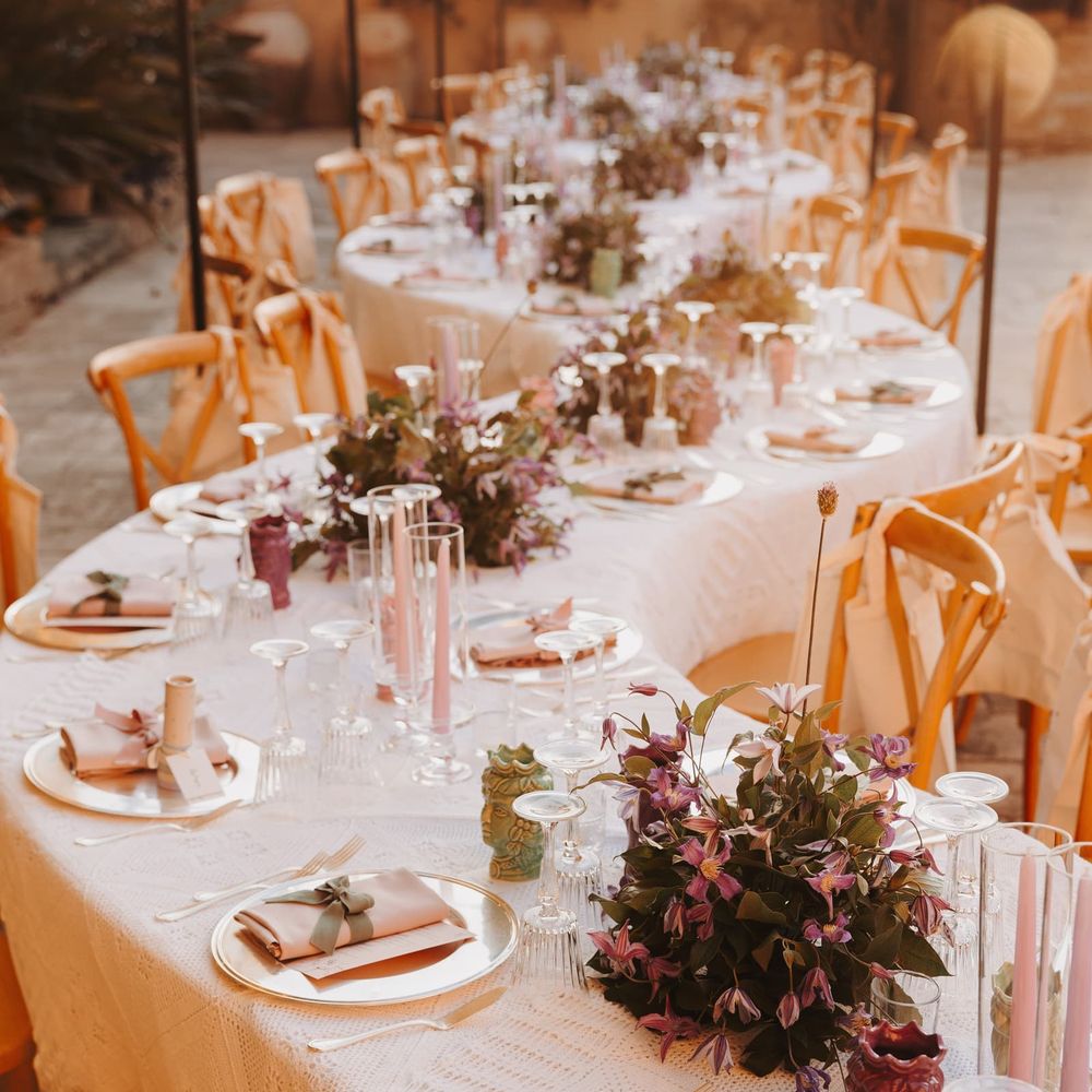 Outdoor reception tables dressed with pink candles, purple blooms and blush napkins on lace linen