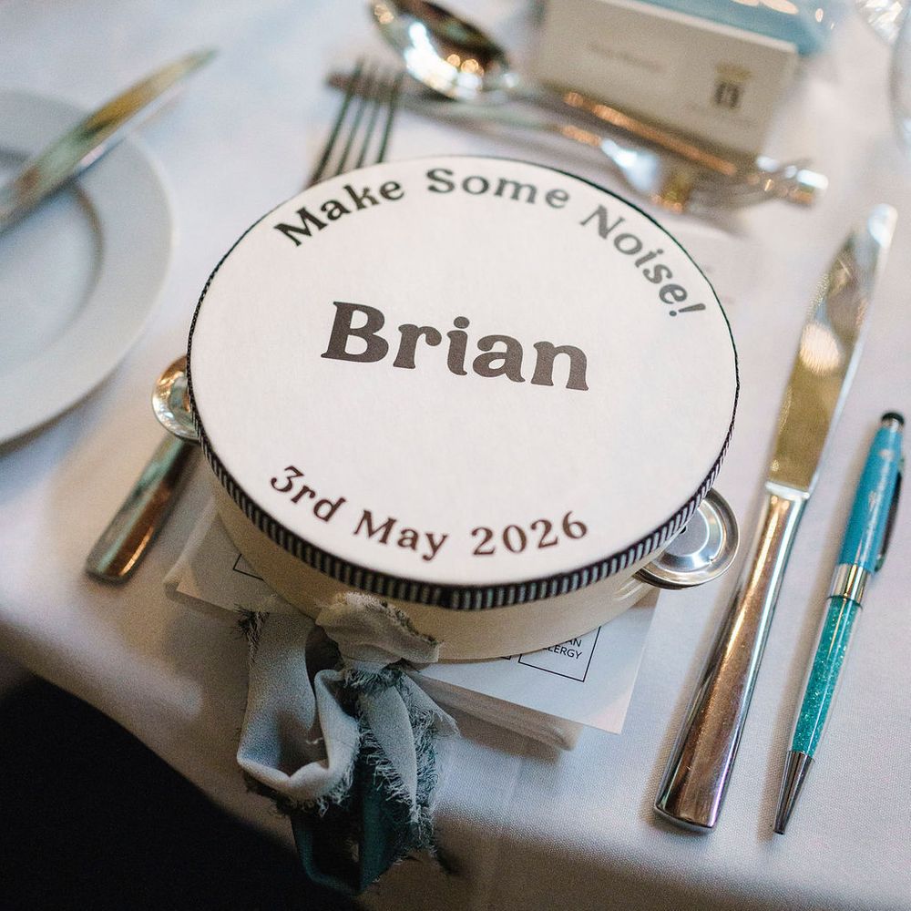 Personalised tambourine place setting reading 'Make Some Noise! Brian' on a laid table