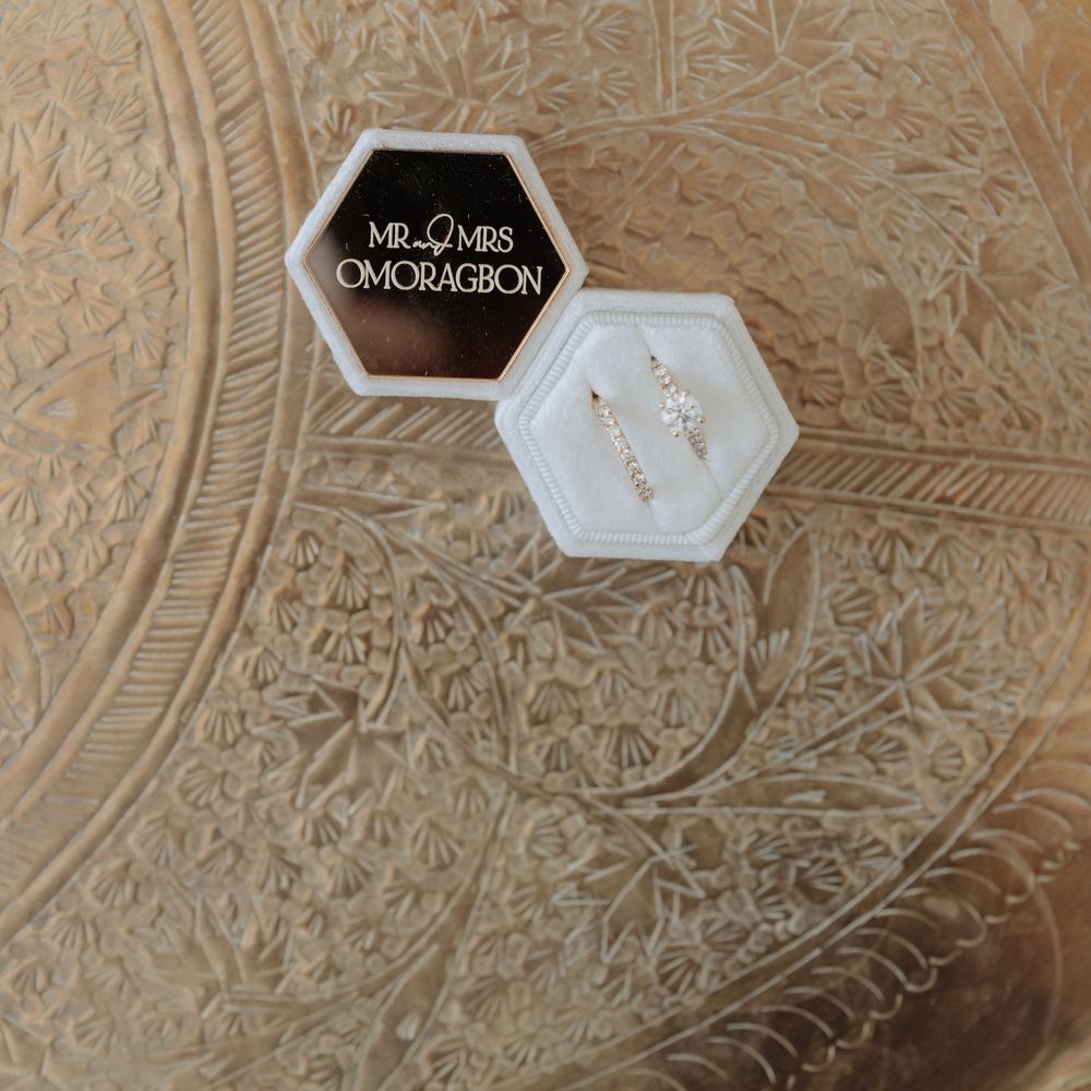 Diamond wedding and engagement rings in a hexagonal velvet box on an engraved brass tray