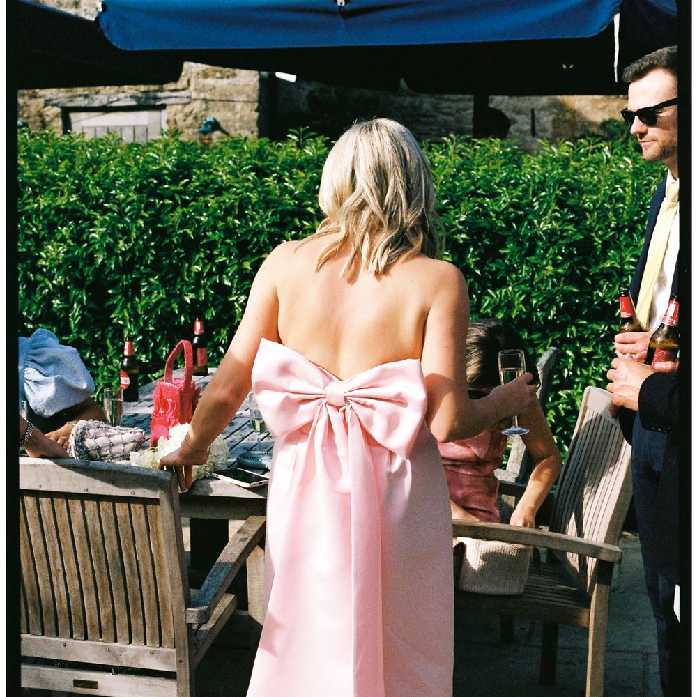 Guest in a strapless pink bow-back gown at a sunny outdoor wedding reception