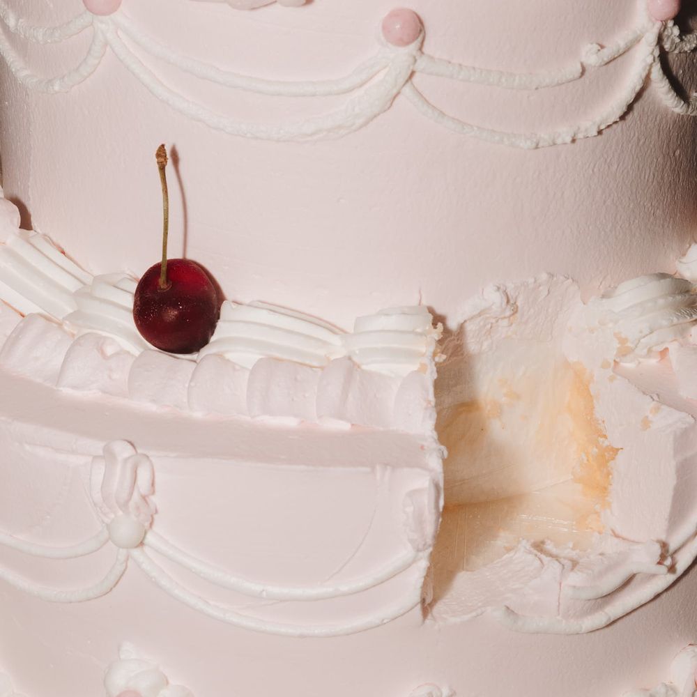 Blush pink piped wedding cake with a fresh cherry and a slice cut away