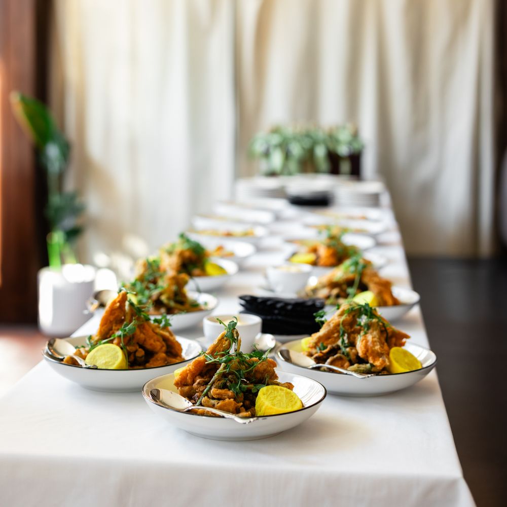 Plated fried starters garnished with fresh herbs and lemon on a long white wedding table