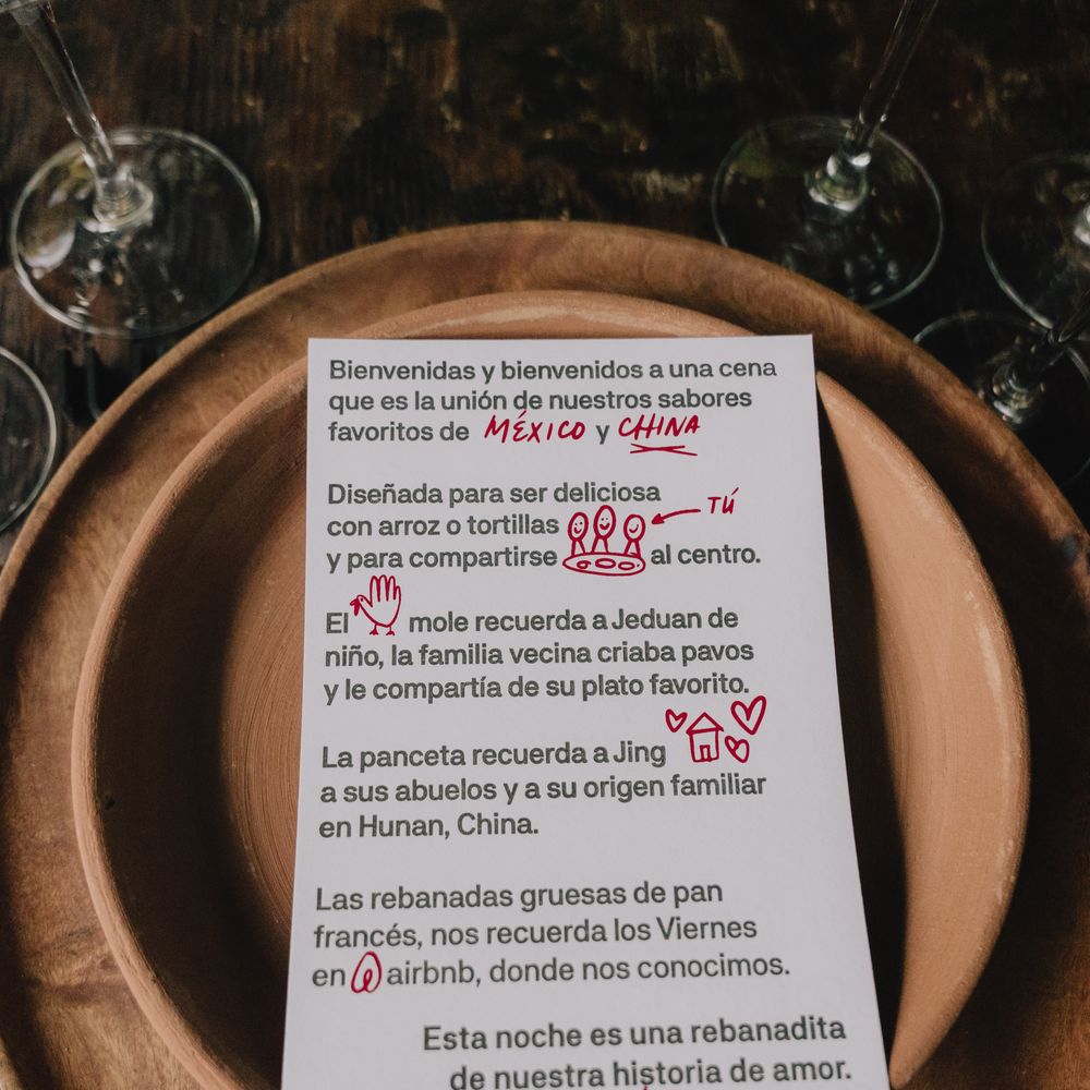 Spanish wedding menu card with red illustrations resting on wooden plates and linen napkin