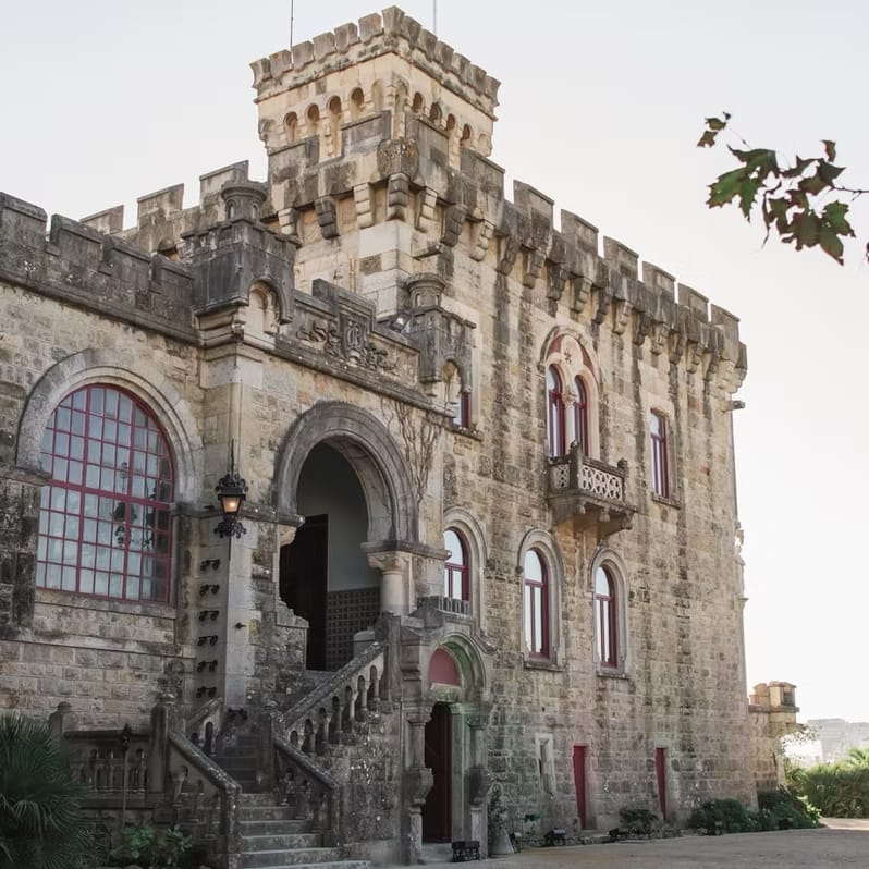 Historic stone castle with crenellated turret, arched windows and a grand external staircase.