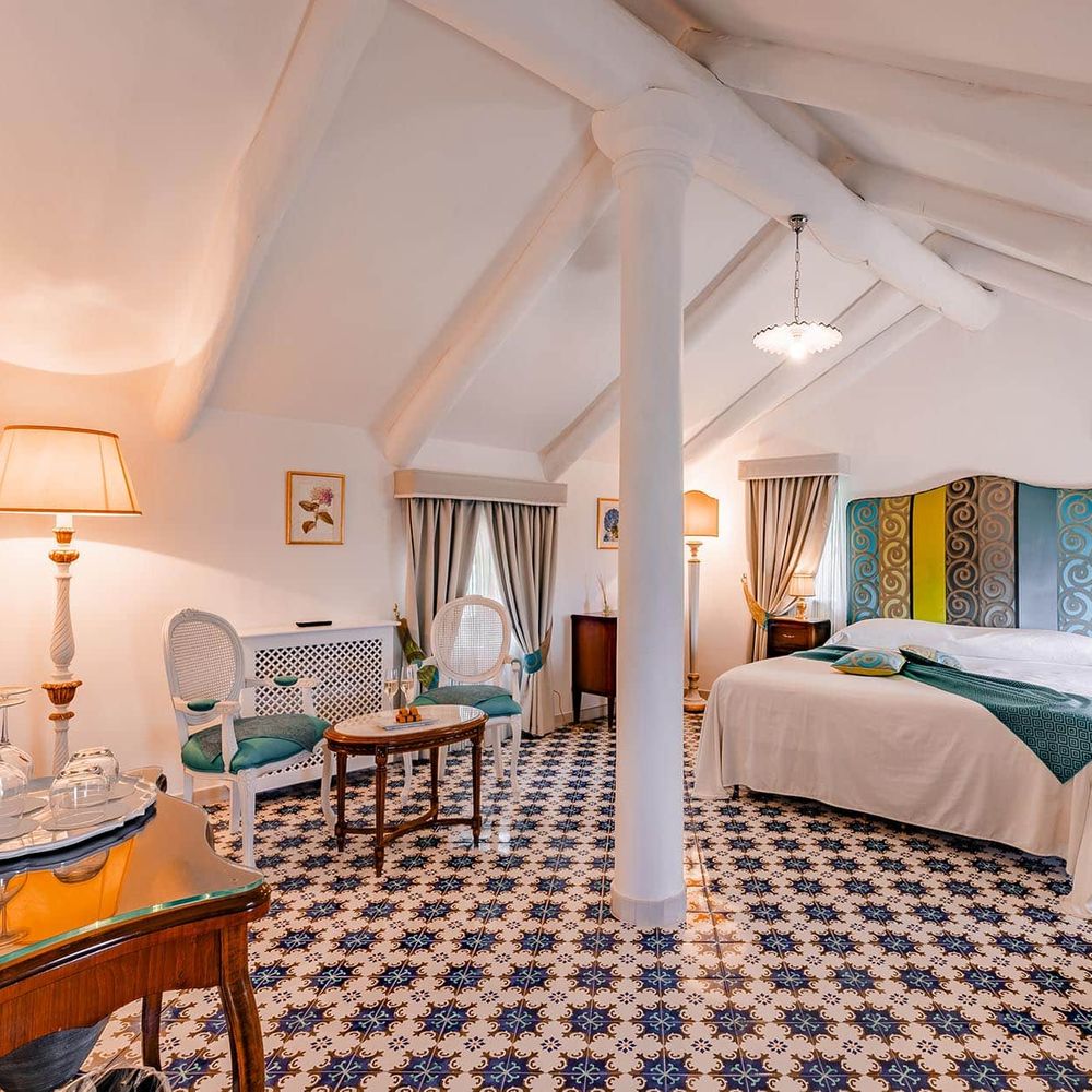 Attic bridal suite with vaulted white beams, patterned tiled floor and elegant antique furnishings