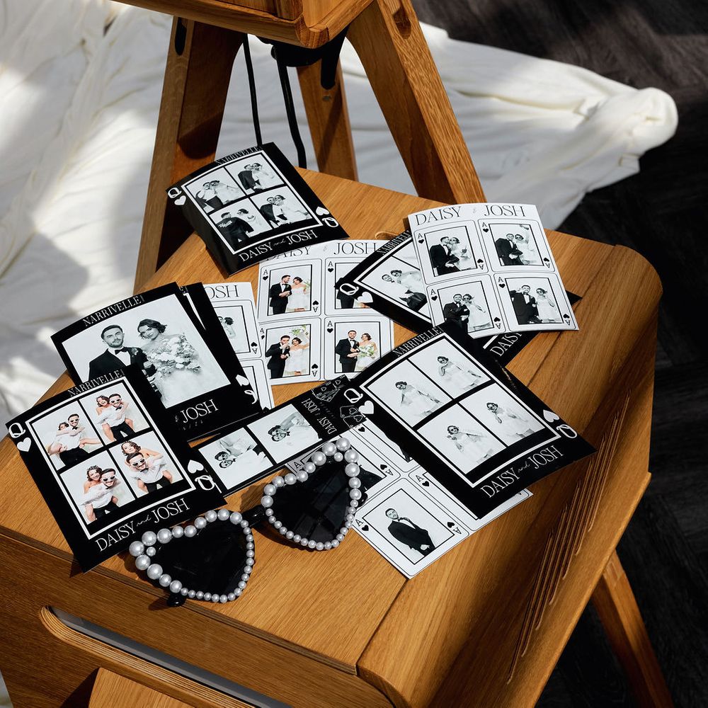 Black and white photo booth strips scattered on a wooden vintage booth with pearl heart sunglasses