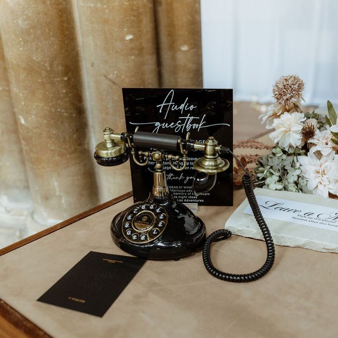 Vintage black telephone audio guestbook with autumnal florals and signage on a table