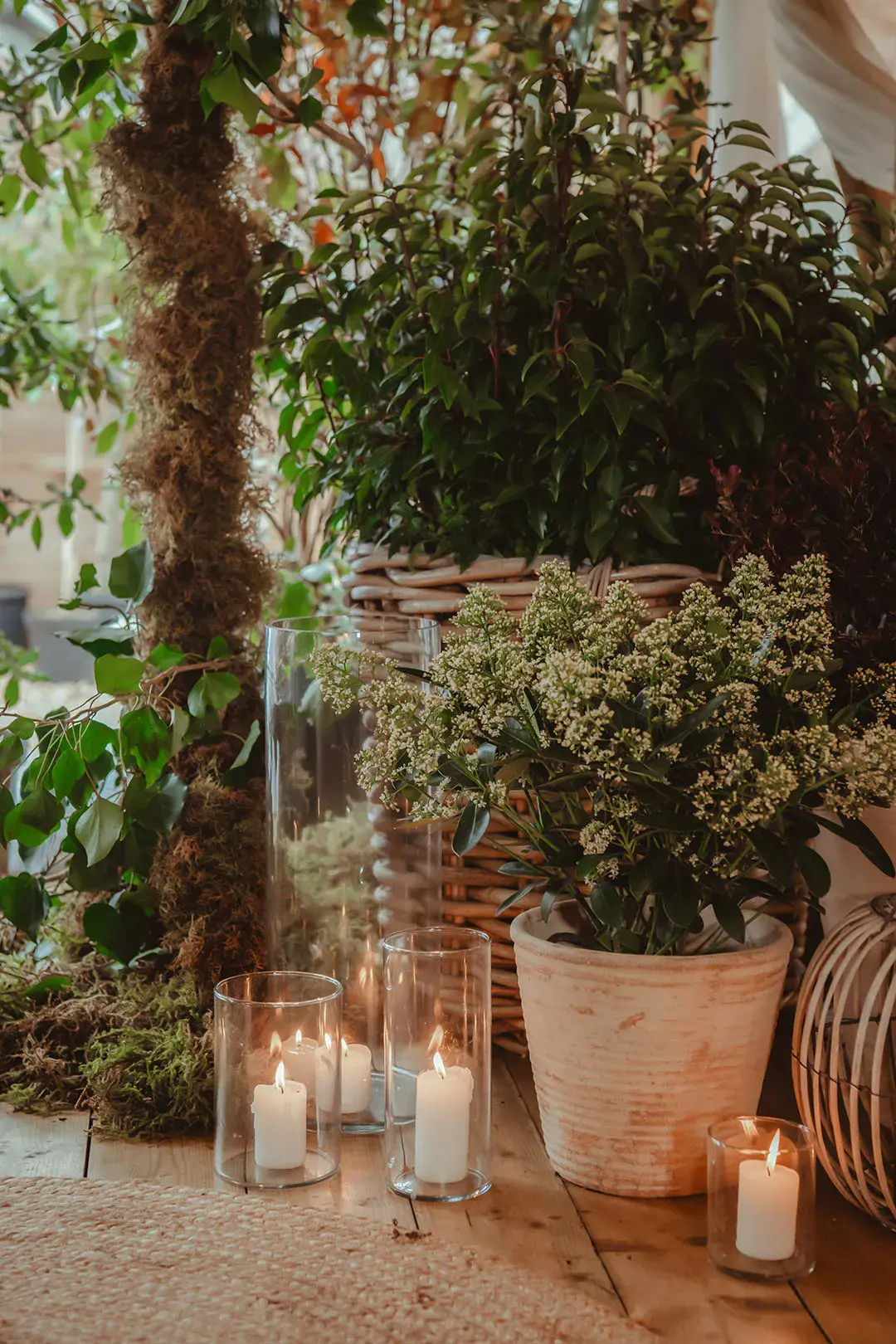 Candles in hurricane vases with plants from the polytunnel at the wedding venue 