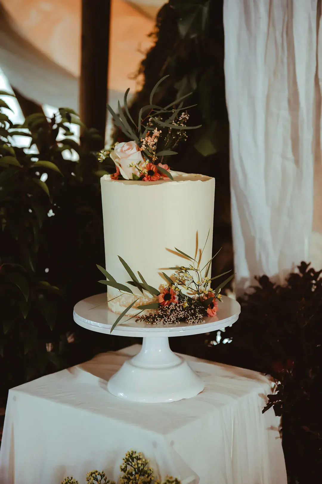 Buttercream frosted wedding cake with foliage and flower decorations 