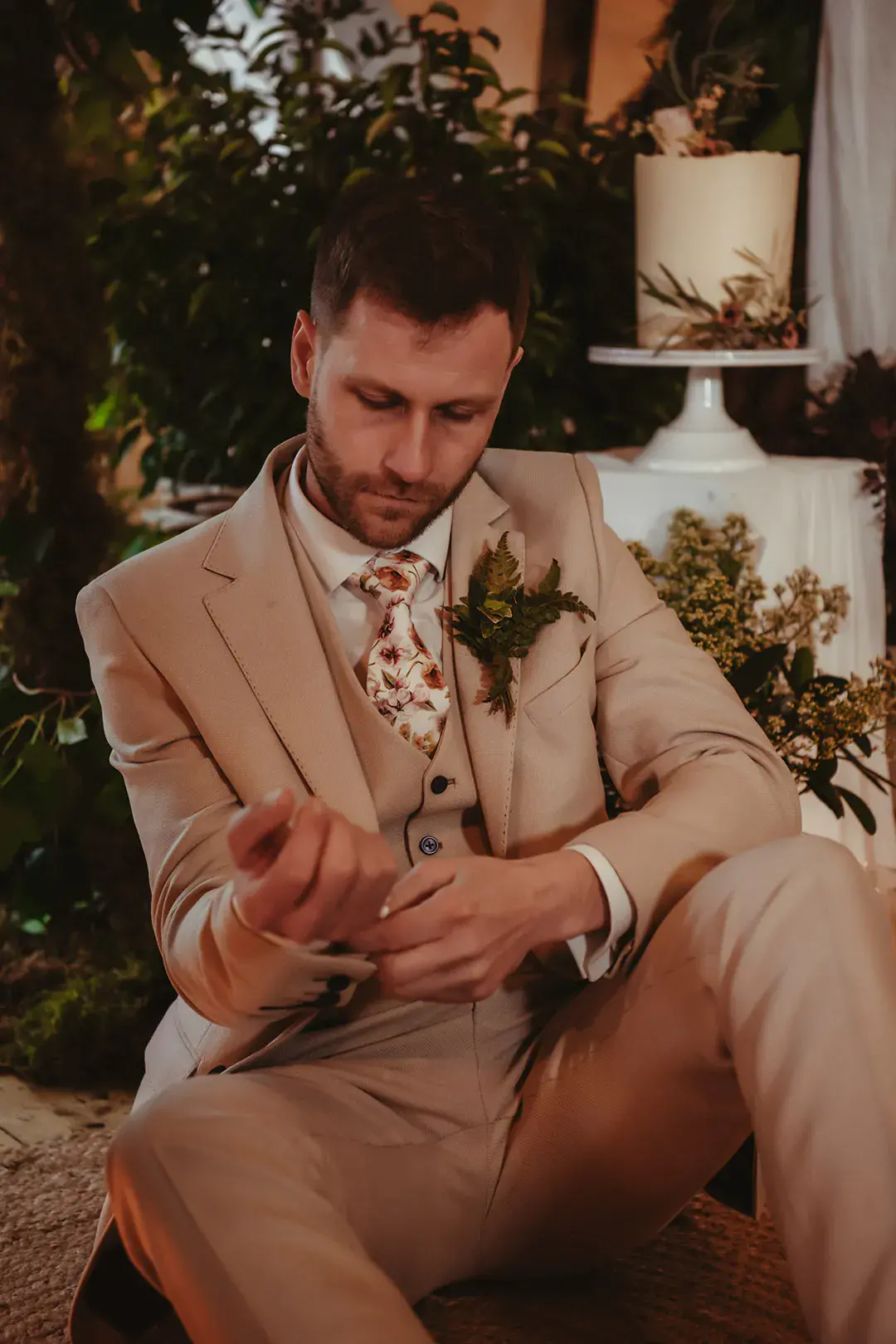 Groom in light grey three piece wedding suit with floral tie and foliage buttonhole 