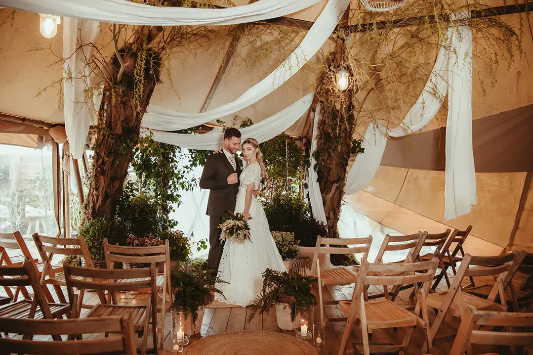 The Garden Tipi no waste wedding with drapery and sustainably sourced wedding fashion with brie in floral wedding dress and groom in brown wedding suit 