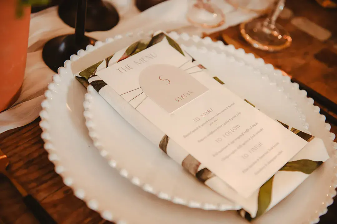 Leaf pattern napkin with classic wedding menu stationery on white plate 