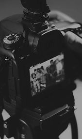 Professional video camera filming an event with people visible on the LCD screen - Videography