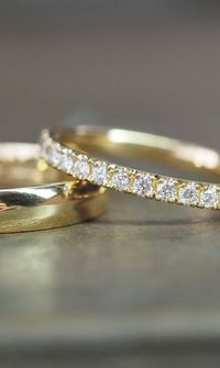 Close-up of a bride’s hand wearing stacked gold wedding rings and a diamond engagement ring - Wedding Rings & Bridal Jewellery