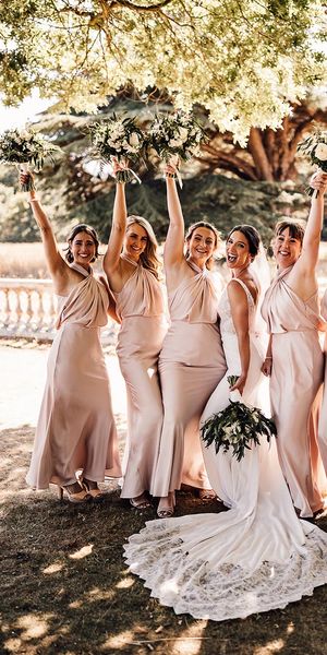 The bride wears a Blue by Enzoani wedding dress with the bridesmaids in blush satin dresses.