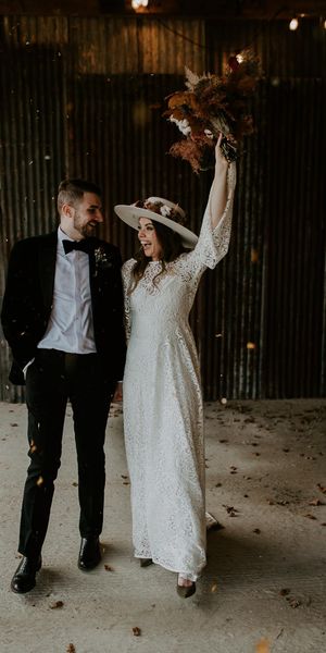 Bride in laser cut lace wedding dress hold up bouquet with Groom