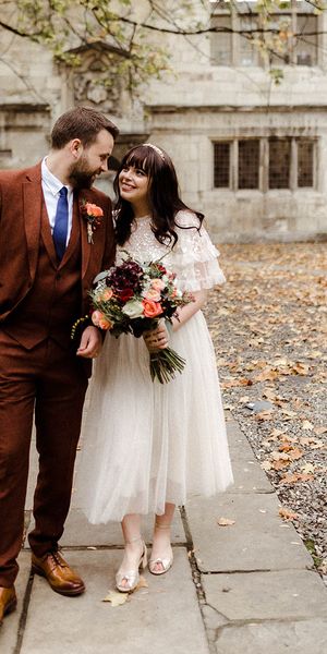Bride in Needle and Thread top and skirt and groom in brown suit look into each other's eyes on their wedding day. 