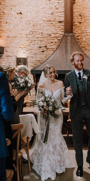 Bride in lace mermaid wedding dress walks back down the aisle with the groom.