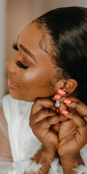 Bride putting on a pair of sparkly silver earrings on her wedding day