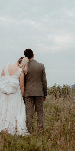 Bride wearing a wedding dress with bow and groom in three piece suit for Middleton Lodge wedding.