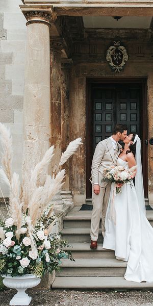 Bride in Jesus Peiro wedding dress and groom in beige suit with pampas grass floral arrangements.